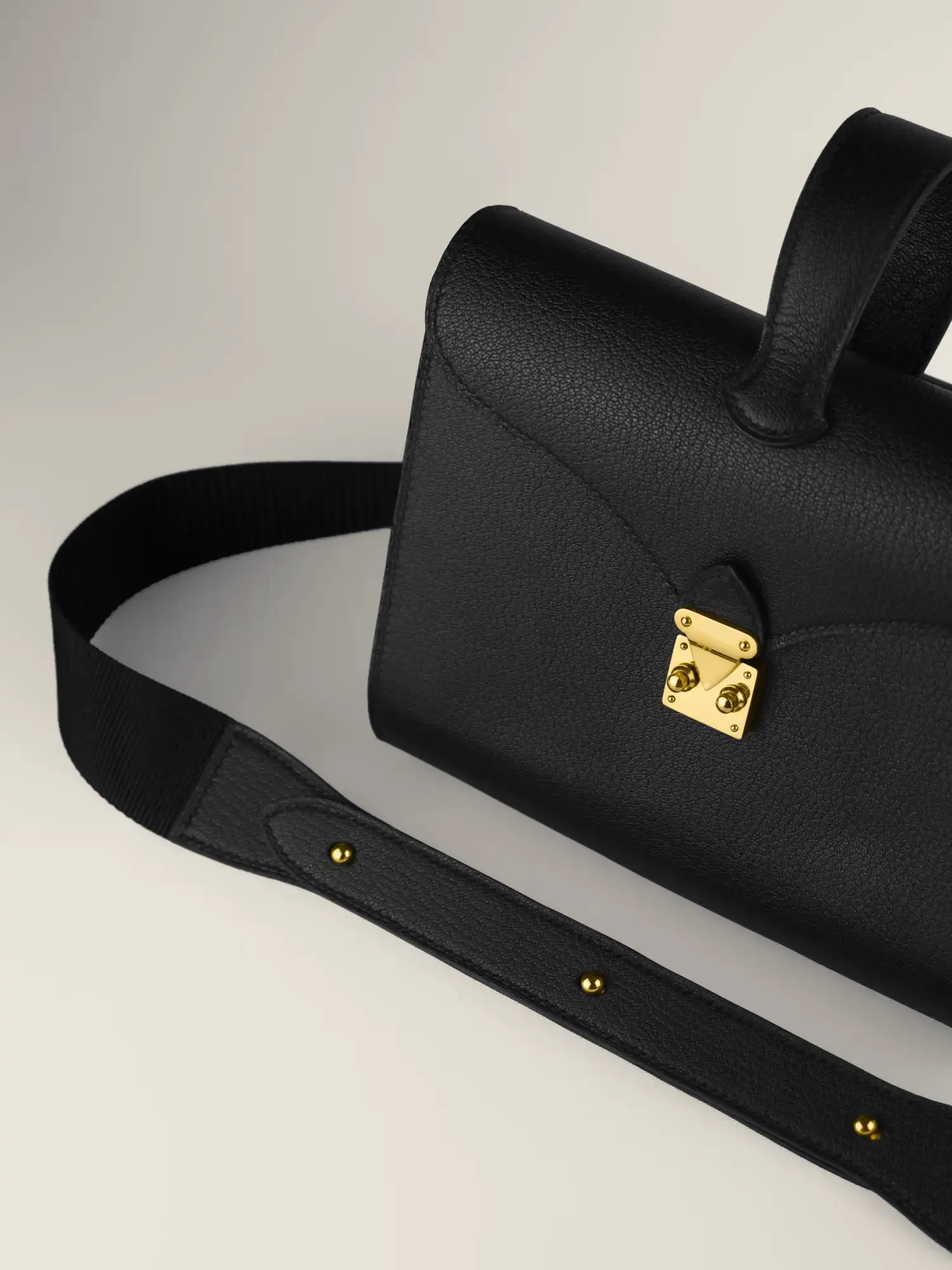 Sac Éclat en cuir de chèvre noir, bouclerie or, posé avec sa bandoulière cuir